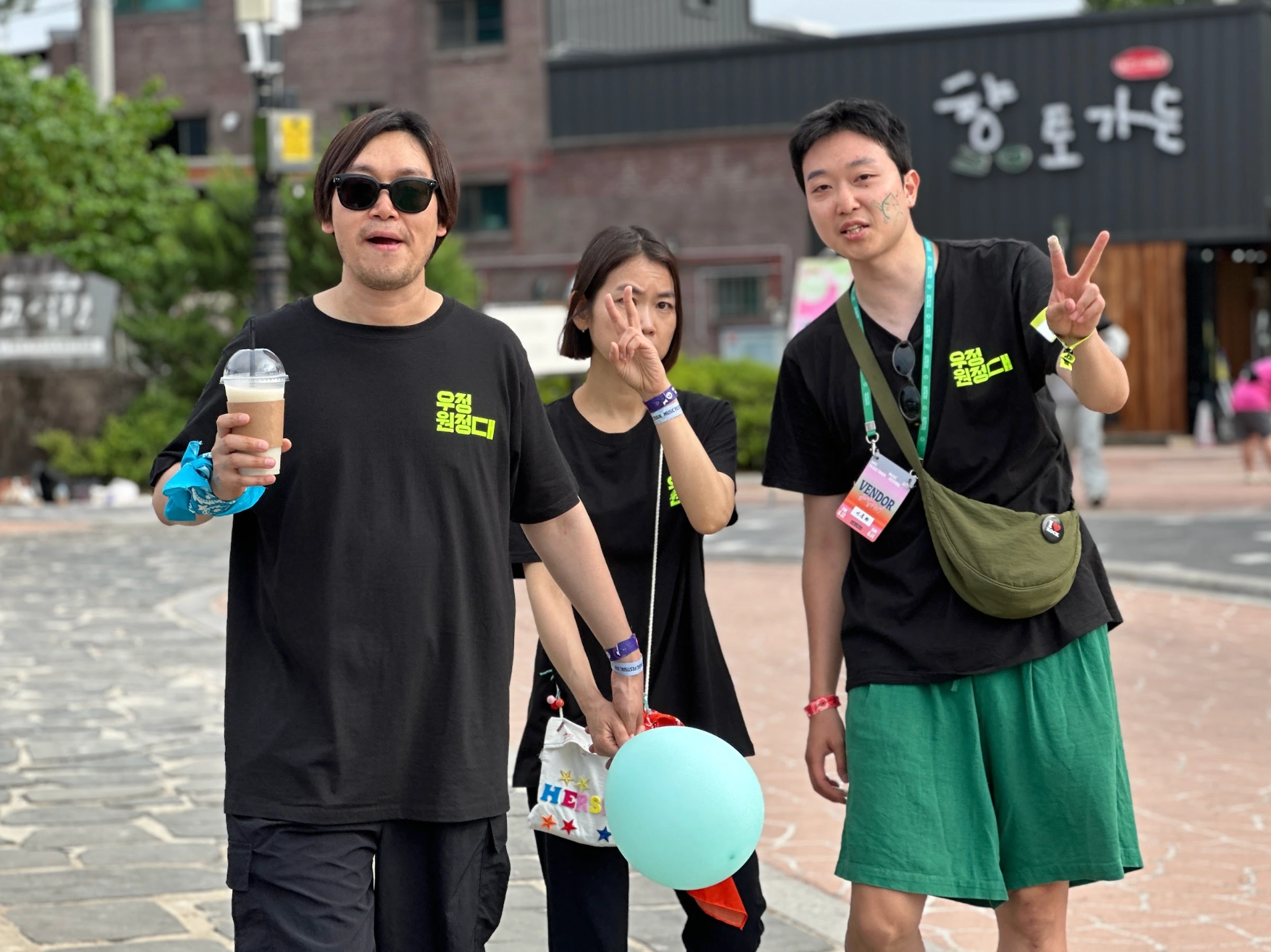 낮의 축제 현장 사진. 3명의 우정원정대원이 함께 포즈를 취하고 있다.