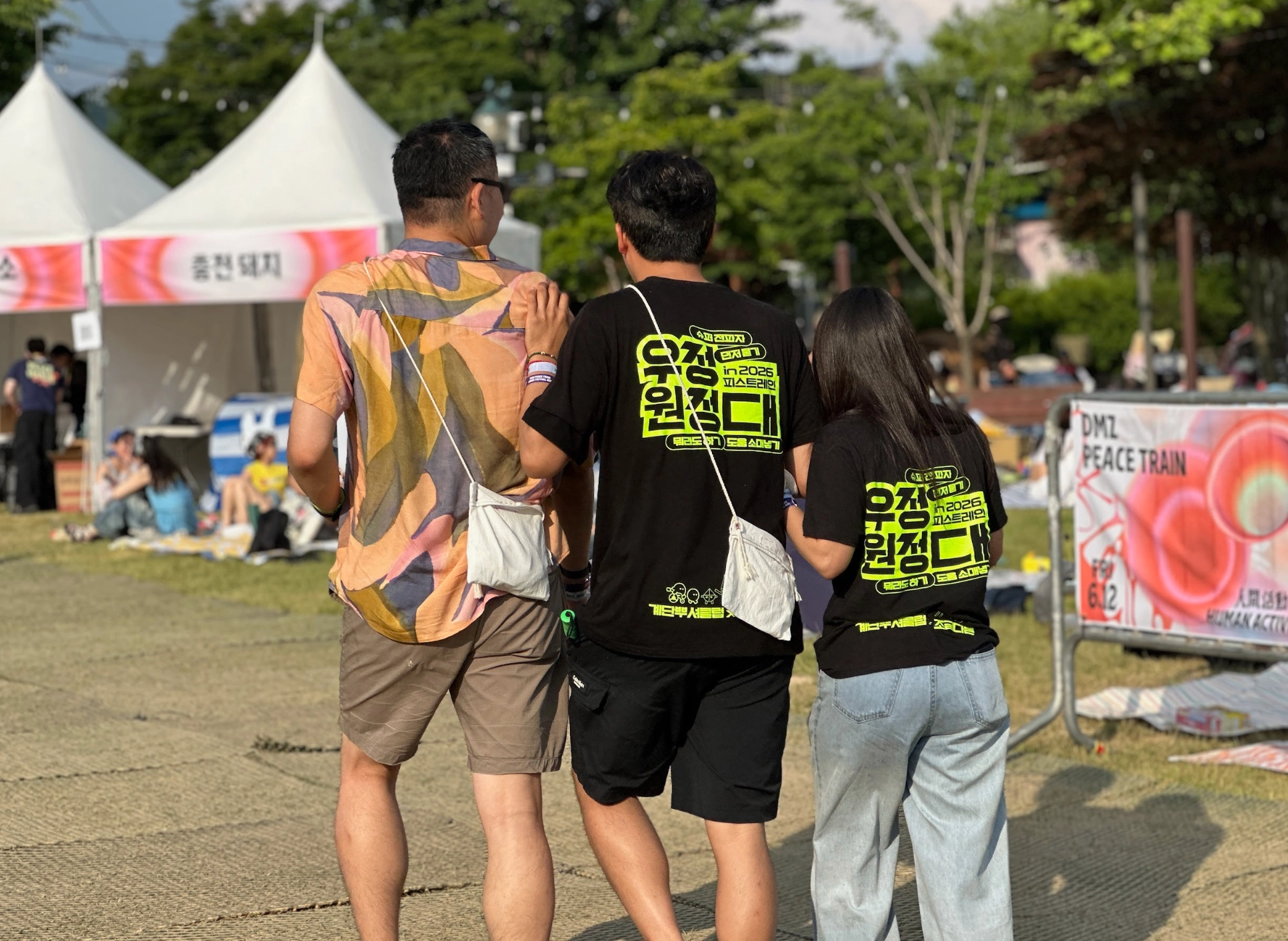 낮의 축제 현장 사진. 3명의 우정원정대원이 나란히 걸어가고 있다.