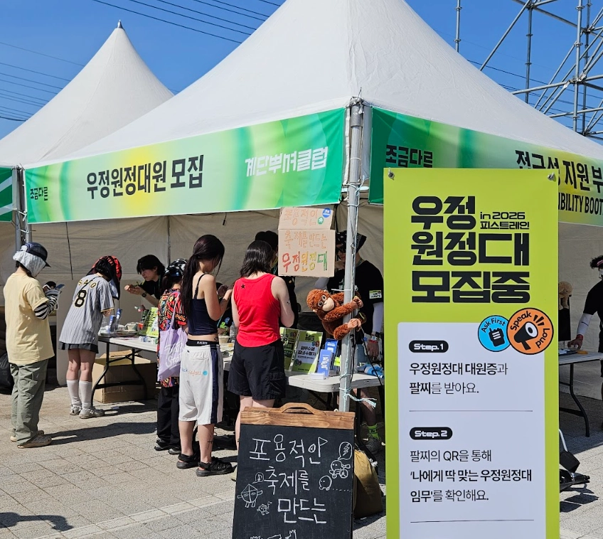우정원정대원 모집 부스 운영 사진. 축제 관객들이 부스 테이블을 살펴보고 있다.